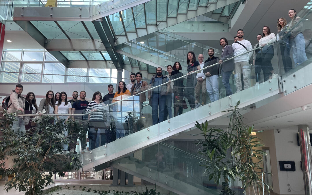 Photo of the participating members during the OpenGLASSroom's 11th Consortium Meeting standing on a glass staircase.