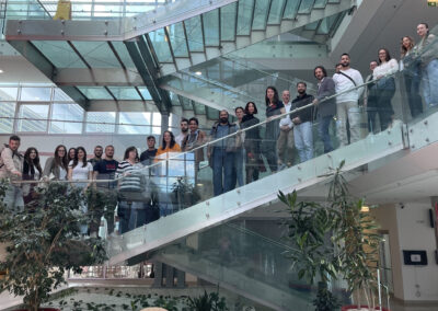 Photo of the participating members during the OpenGLASSroom's 11th Consortium Meeting standing on a glass staircase.