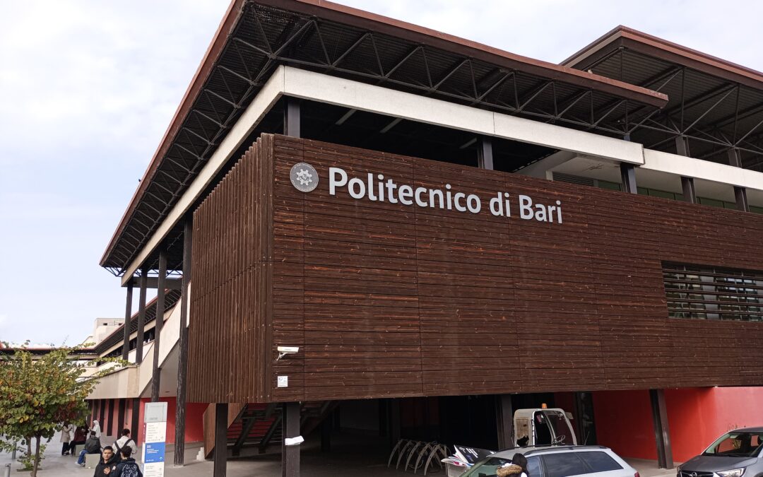 The picture shows a building panelled with wood. On one of the walls is the inscription “Politecnico di Bari” and next to it is the university logo.